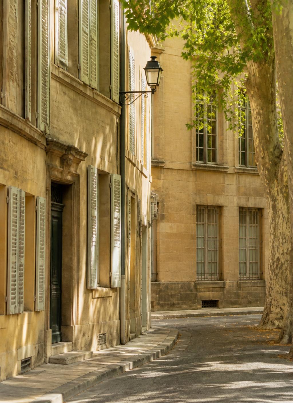 Quiet sunlit street of pale stone facades and wooden shutters in Aix-en-Provence