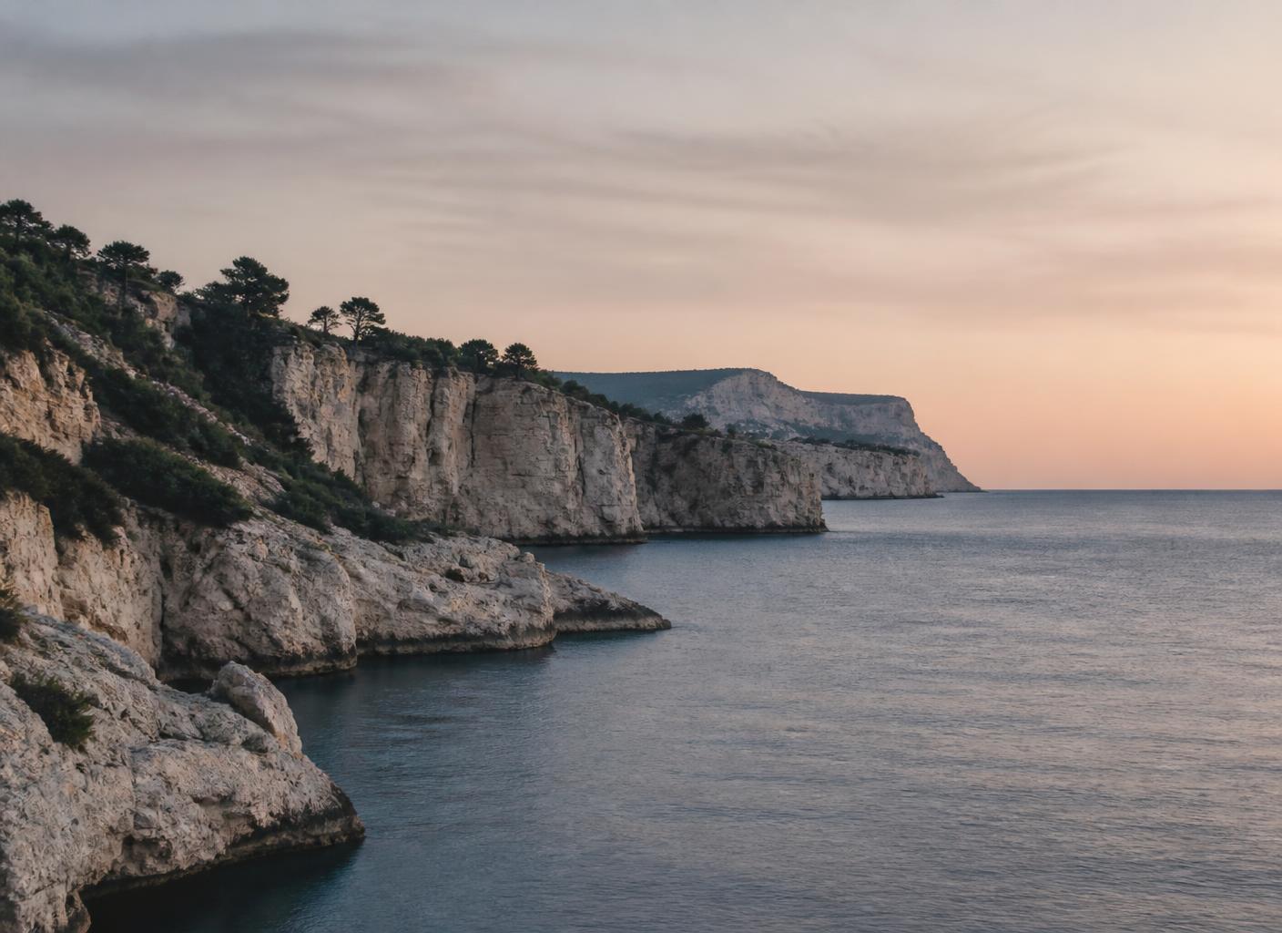 Pale limestone cliffs meeting the calm Mediterranean sea at dusk near Cassis